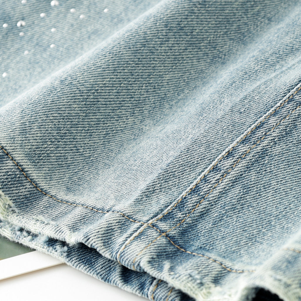 Women's high-waisted, washed blue denim mini skirt with rhinestone details and frayed edges; versatile and stylish.