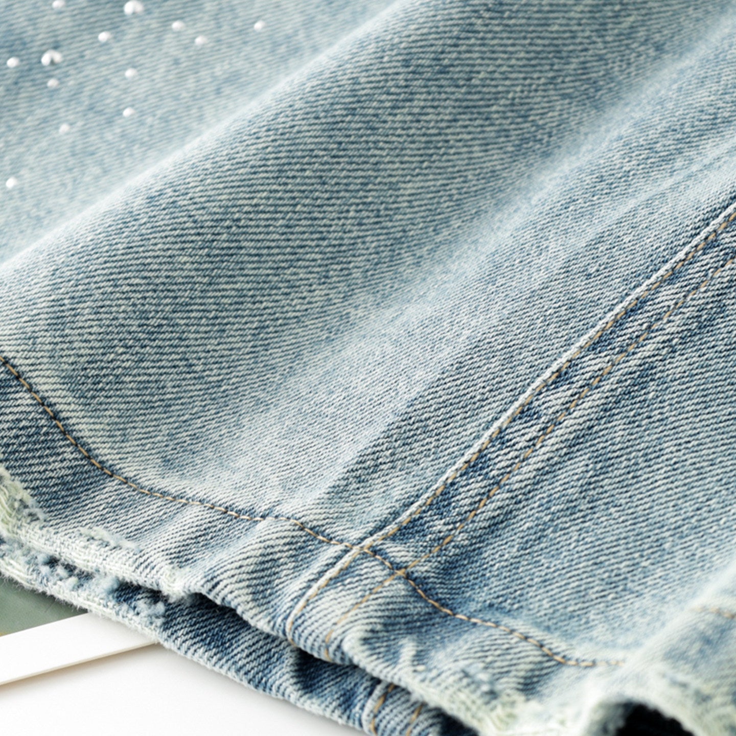 Women's high-waisted, washed blue denim mini skirt with rhinestone details and frayed edges; versatile and stylish.