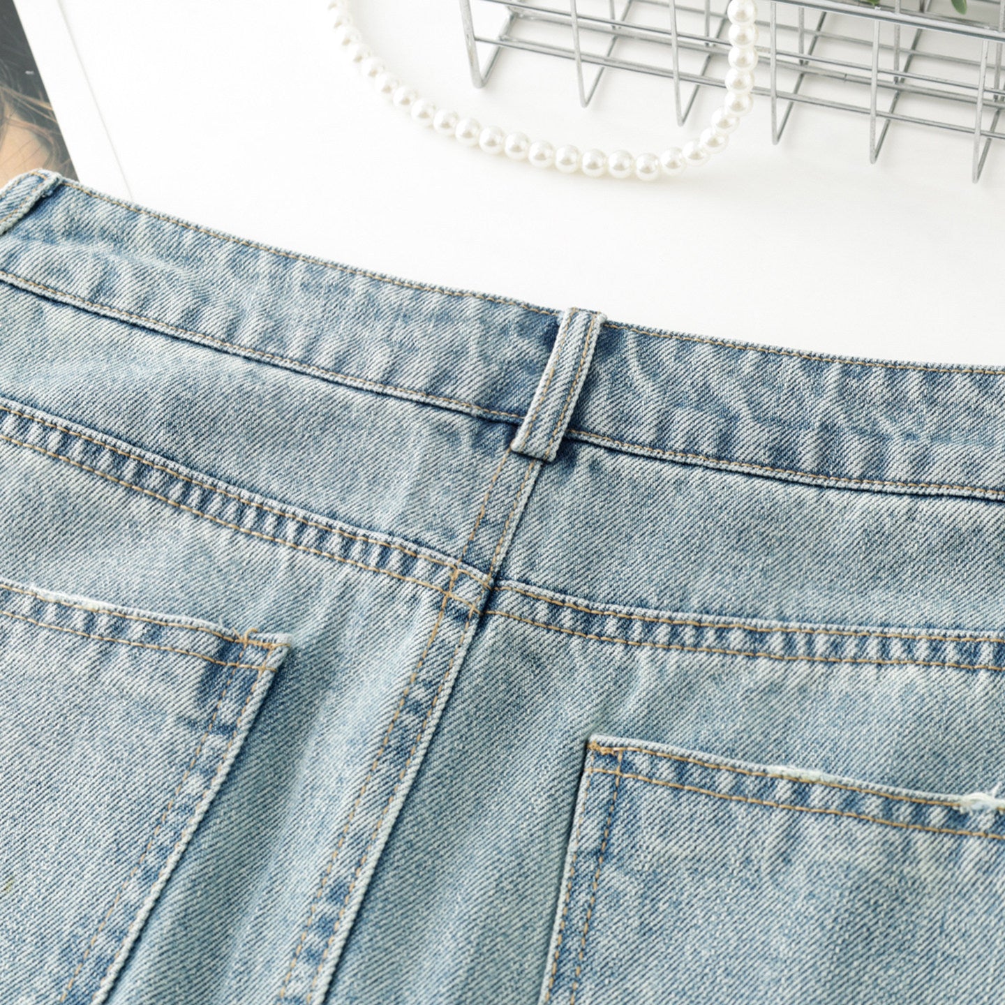 Women's high-waisted, washed blue denim mini skirt with rhinestone details and frayed edges; versatile and stylish.